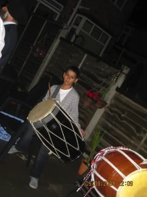 AJ as a child playing dhol